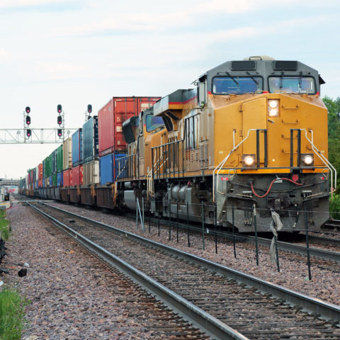 Two yellow locomotives and double stack freight train