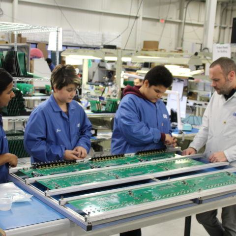 Students in blue lab coats learning about circut boards