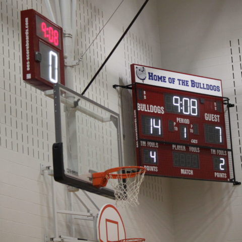 An indoor basketball scoreboard with a shot clock above the basketball net.