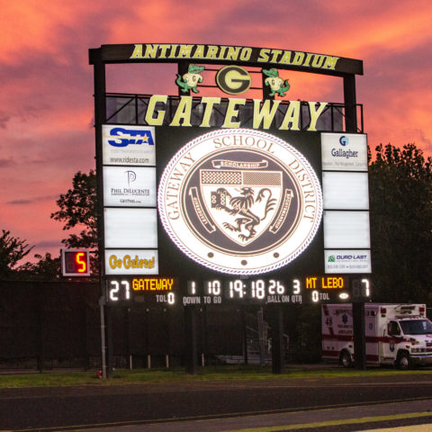 The video display at Gateway High School with the sun setting behind it. Sky is pink and orange in color.