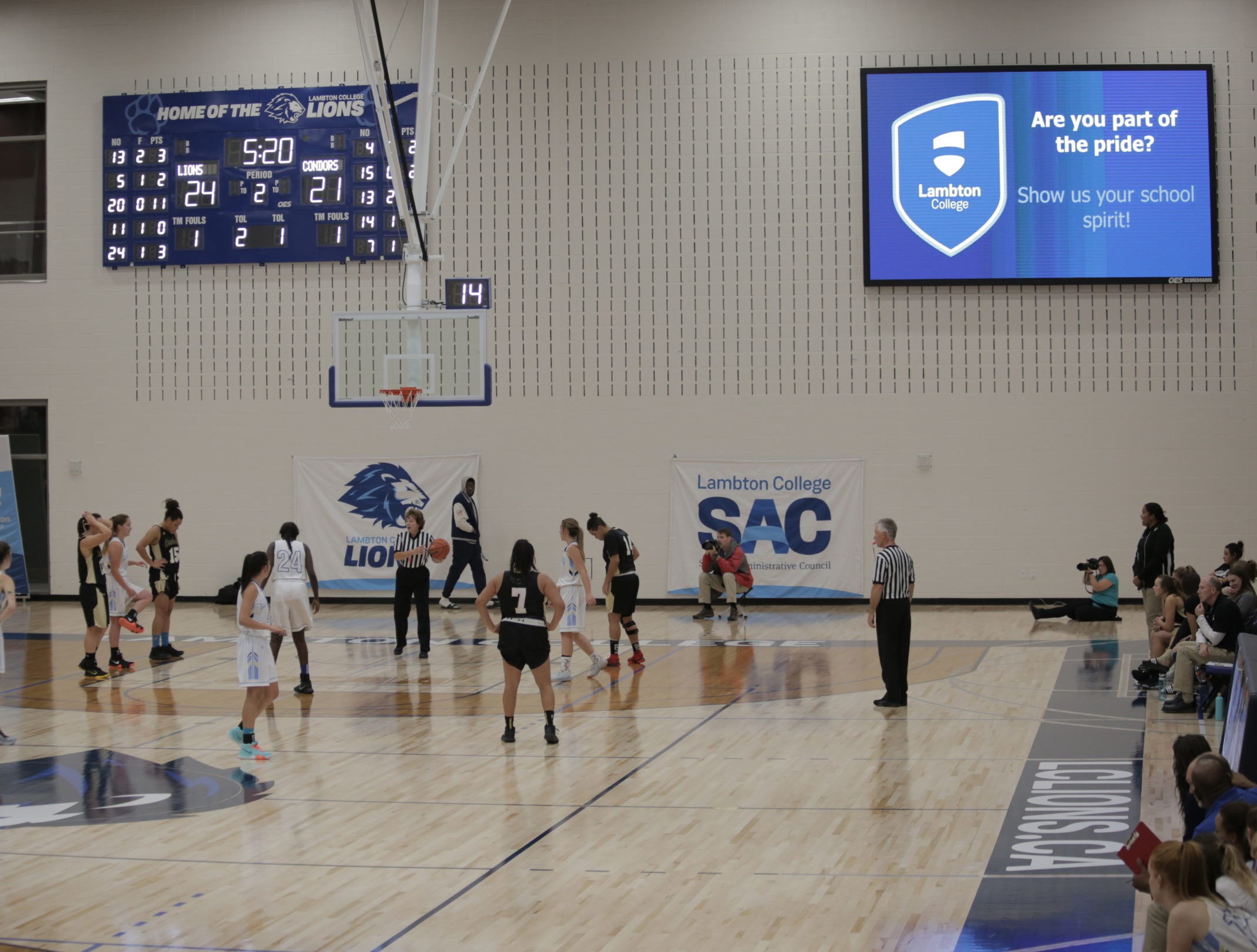 basketball game in front of scoreboard and screen