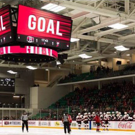 Hockey arena with large video scoreboard displaying 'goal'.