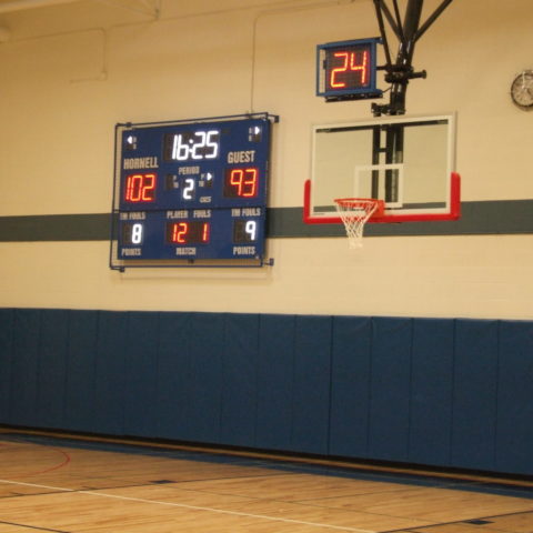 An indoor basketball scoreboard with a shot clock above the basketball net.