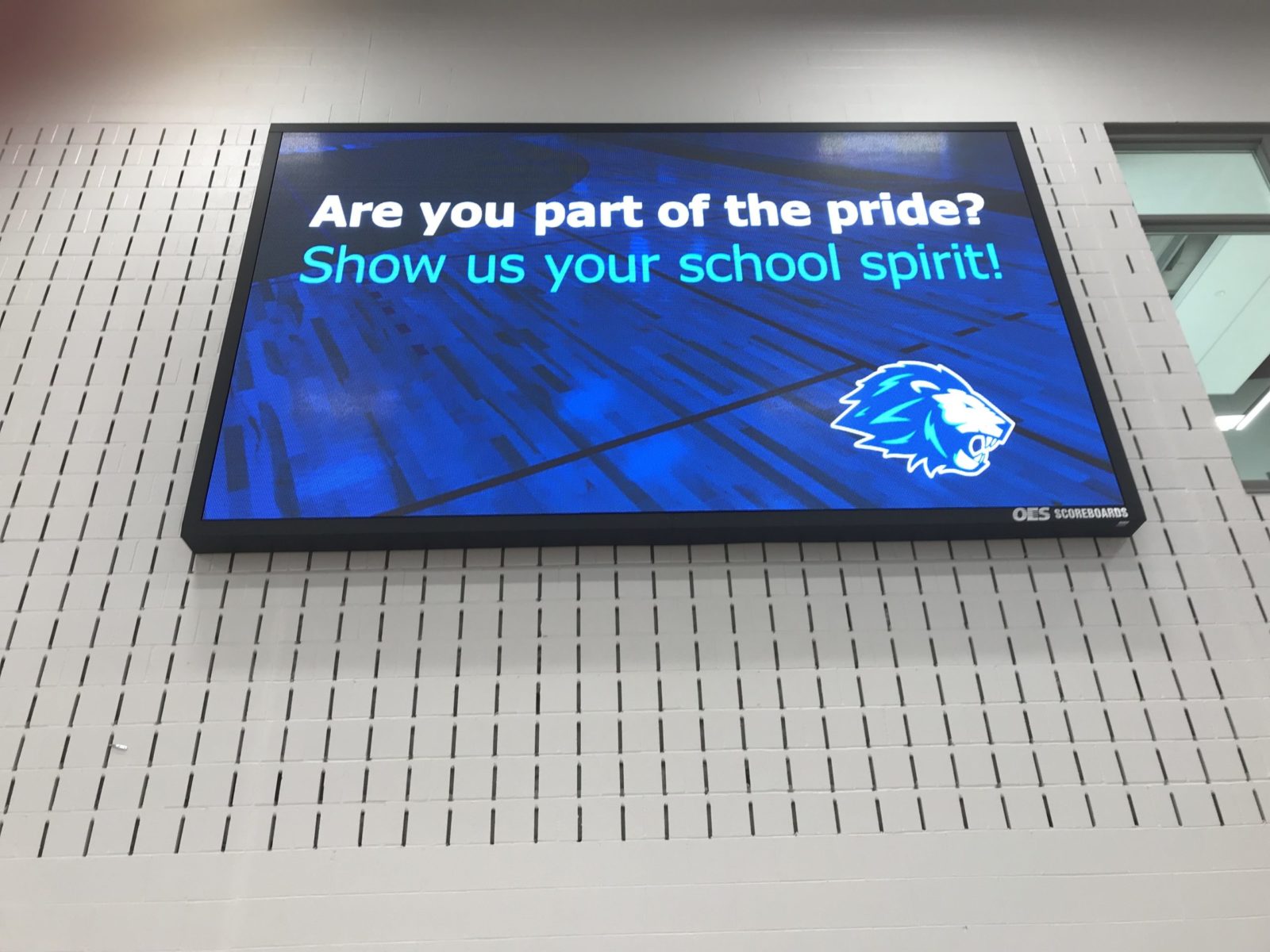 An indoor scoreboard with words "are you part of the pride?'