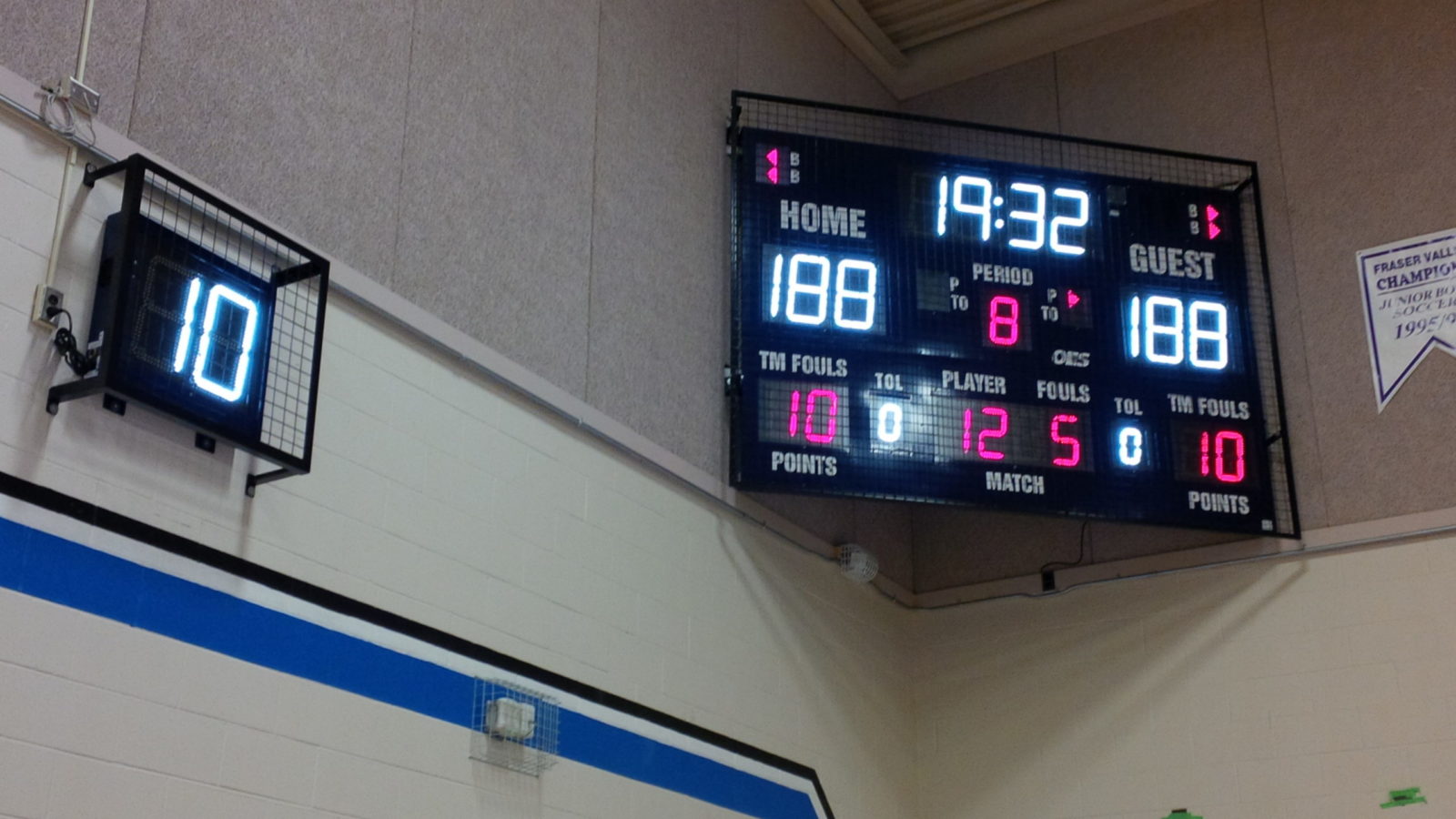 An indoor basketball scoreboard with a shot clock above the basketball net.