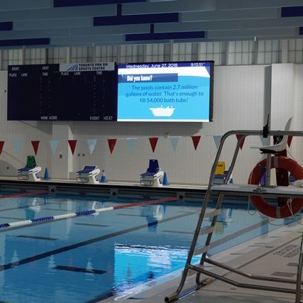 video display on a wall with a swimming pool and lifeguard chair in the foreground