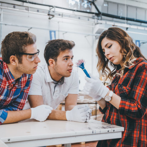 Women holding a bunch of wires while two younger men listen attentively.