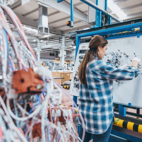 Young women working on a large circuit with wires in the foreground.