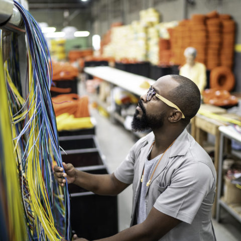 Man measuring colourful wires with other staff in the background.