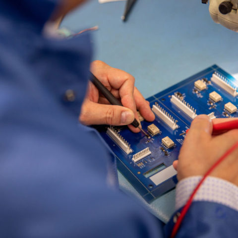 Close up of hands fixing a circuit board.