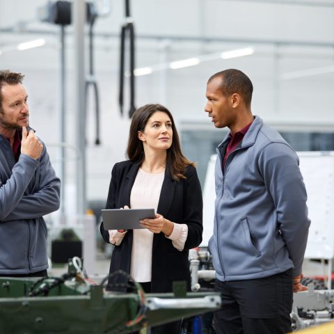 Professionals talking while on a factory floor.